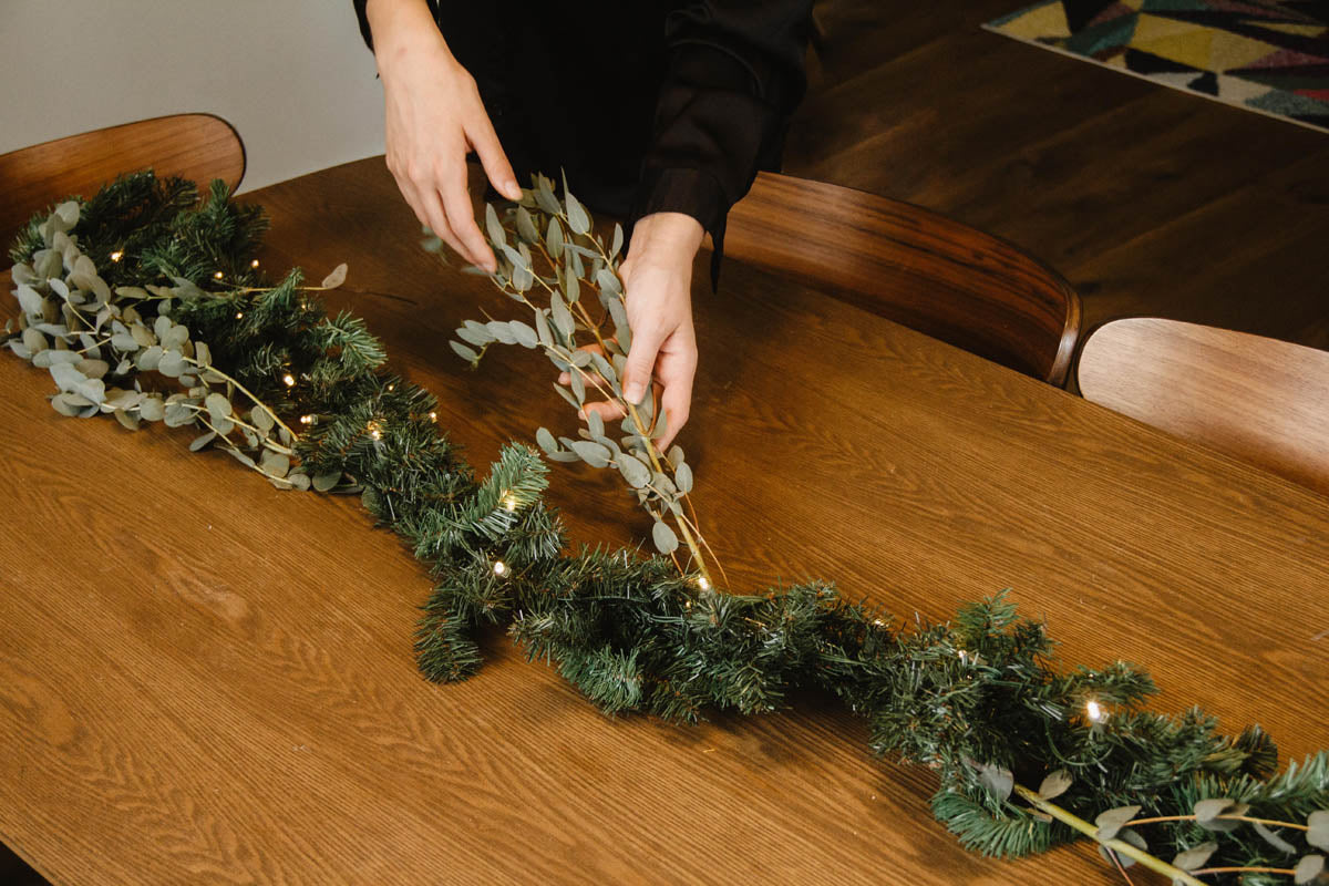 greenery being placed on garland on dining room table
